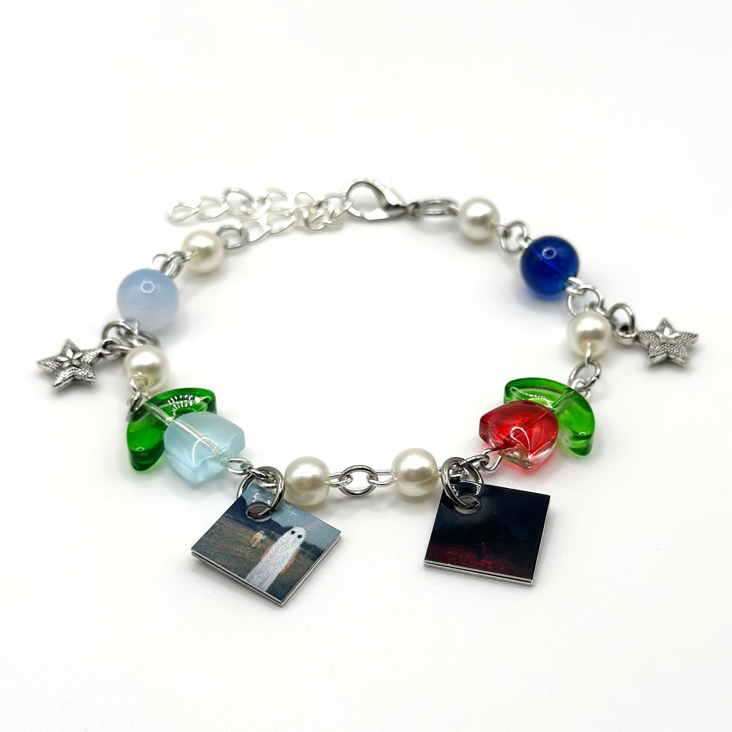 A charm bracelet with miniature (half inch) metal Phoebe Bridgers albums and lobster claw clasp closure.