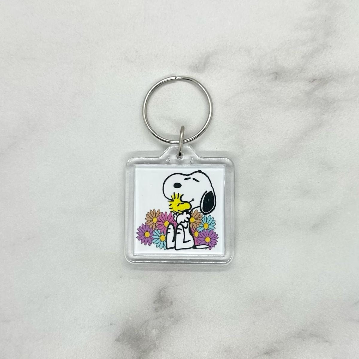 Cute acrylic photo keychain Snoopy hugging Woodstock surrounded by flowers. 
