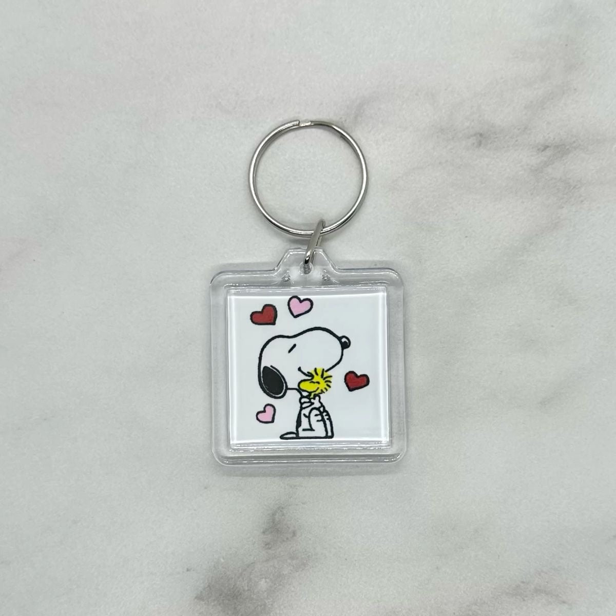 Cute acrylic photo keychain of Snoopy hugging Woodstock with hearts.