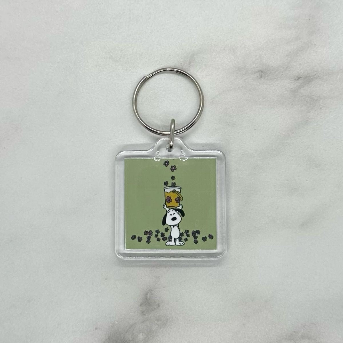 Cute acrylic photo keychain of Snoopy catching flowers with a bucket.