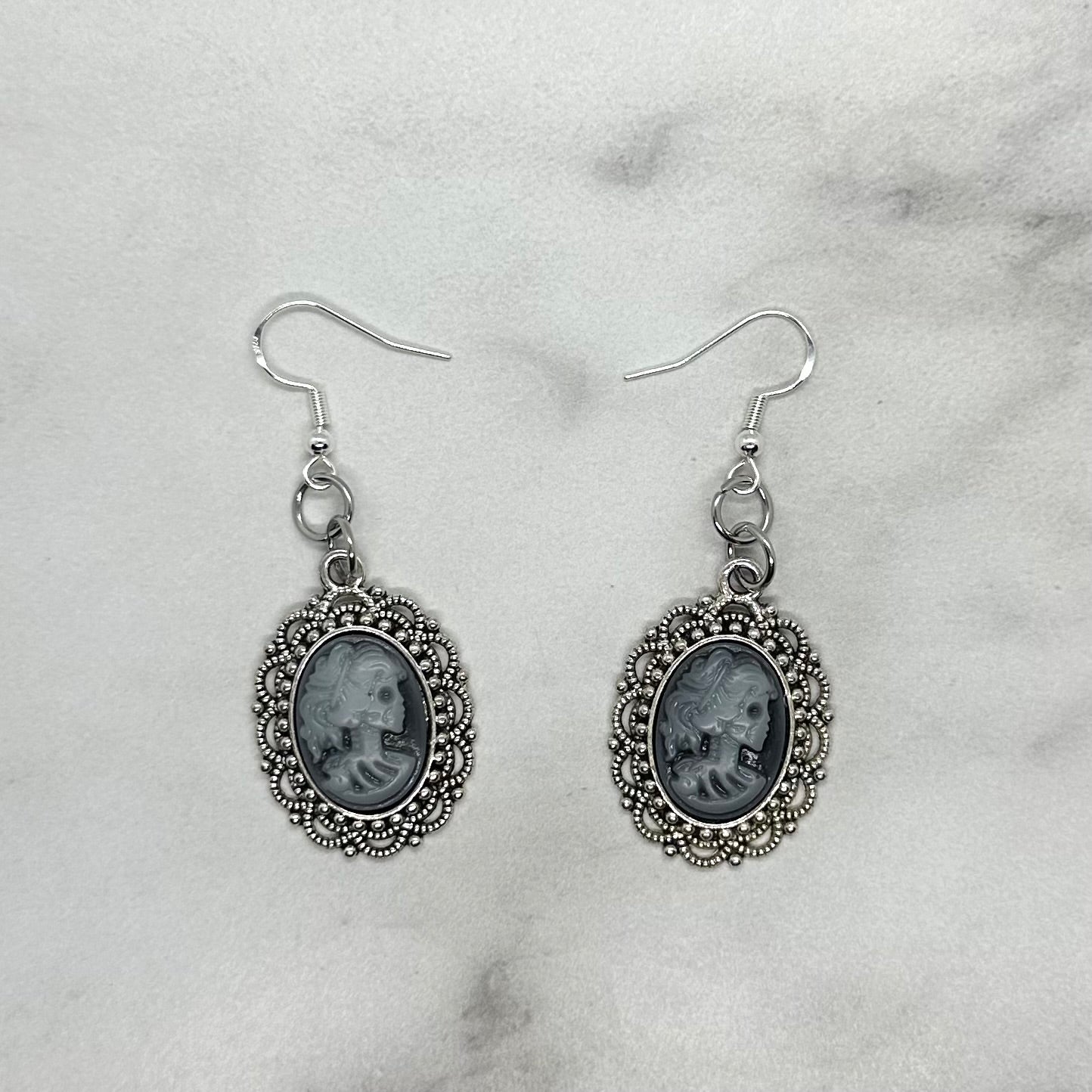 Pair of silver cameo earrings depicting queen goth emo skeleton. Sterling Silver ear wire closure.