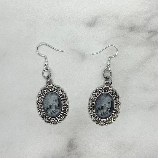 Pair of silver cameo earrings depicting queen goth emo skeleton. Sterling Silver ear wire closure.